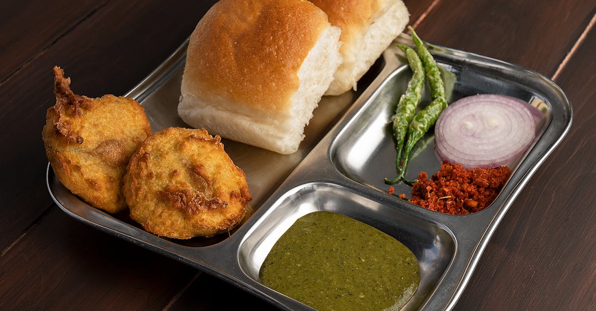 delicious maharashtrian vada pav served with chutney and spices on a stainless steel plate