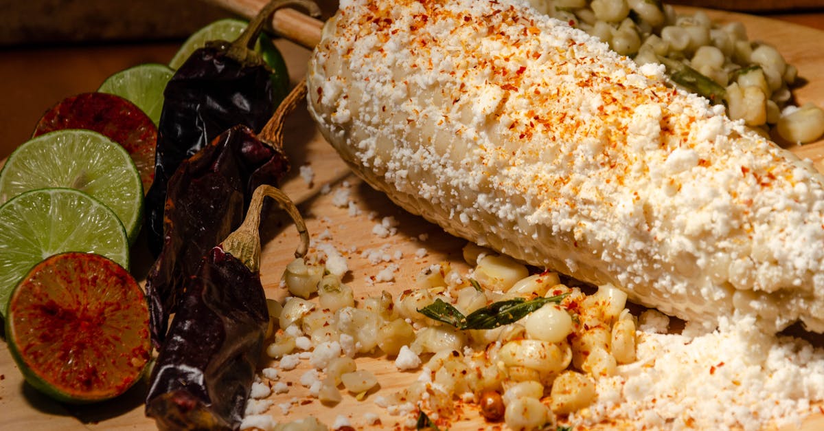 delicious mexican elote served with limes and dried chili peppers on a wooden board