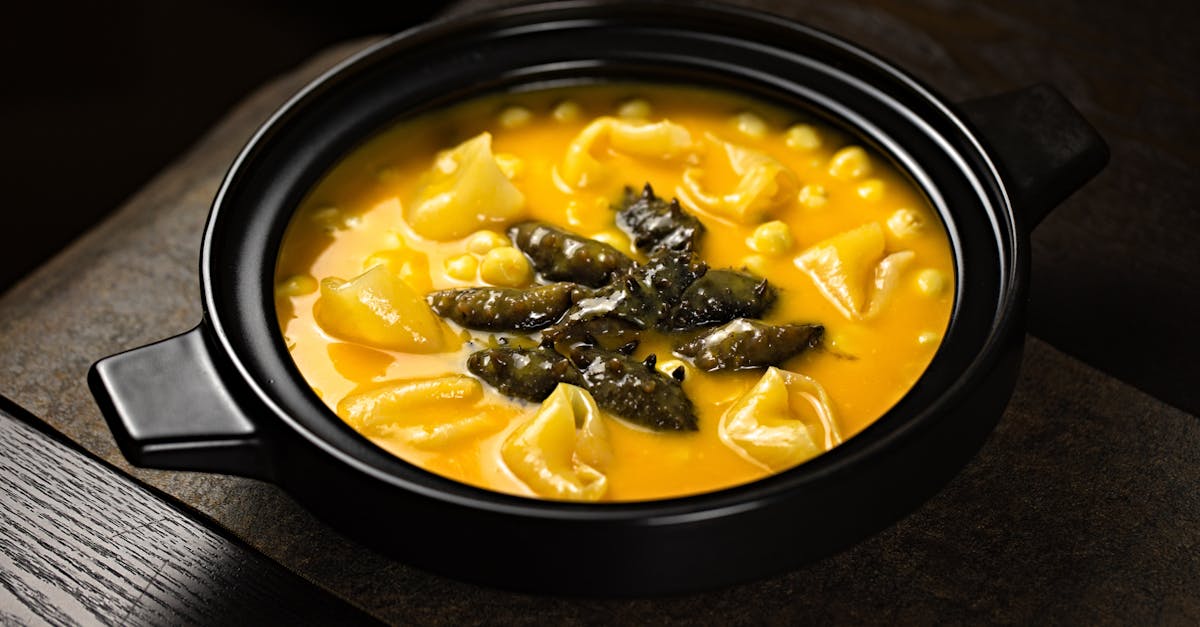 delicious pumpkin soup with tortellini and mushrooms in a black ceramic bowl on a wooden tray