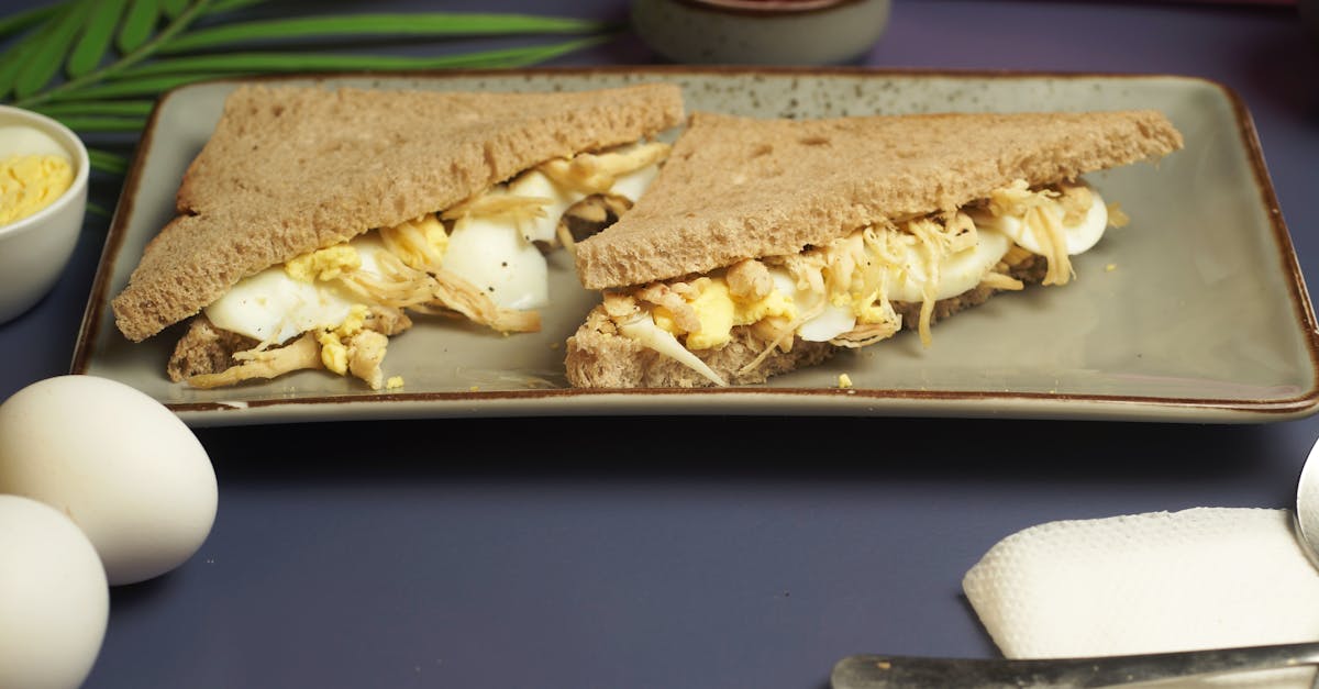 delicious scrambled and boiled egg sandwich on whole wheat bread with sauce and utensils