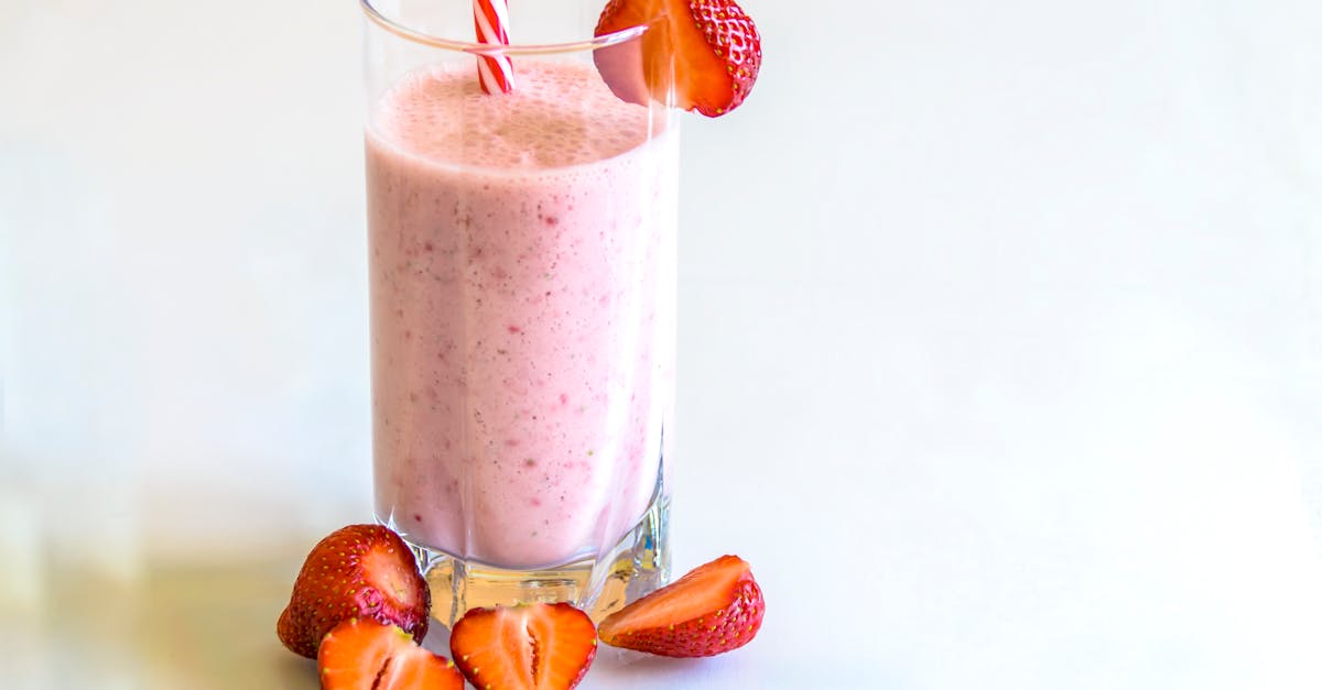 delicious strawberry smoothie in a glass with fresh strawberries and a striped straw on a light back 4