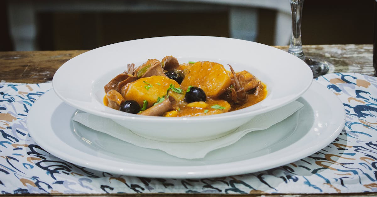 delicious traditional angolan stew featuring root vegetables and dark olives in a white bowl