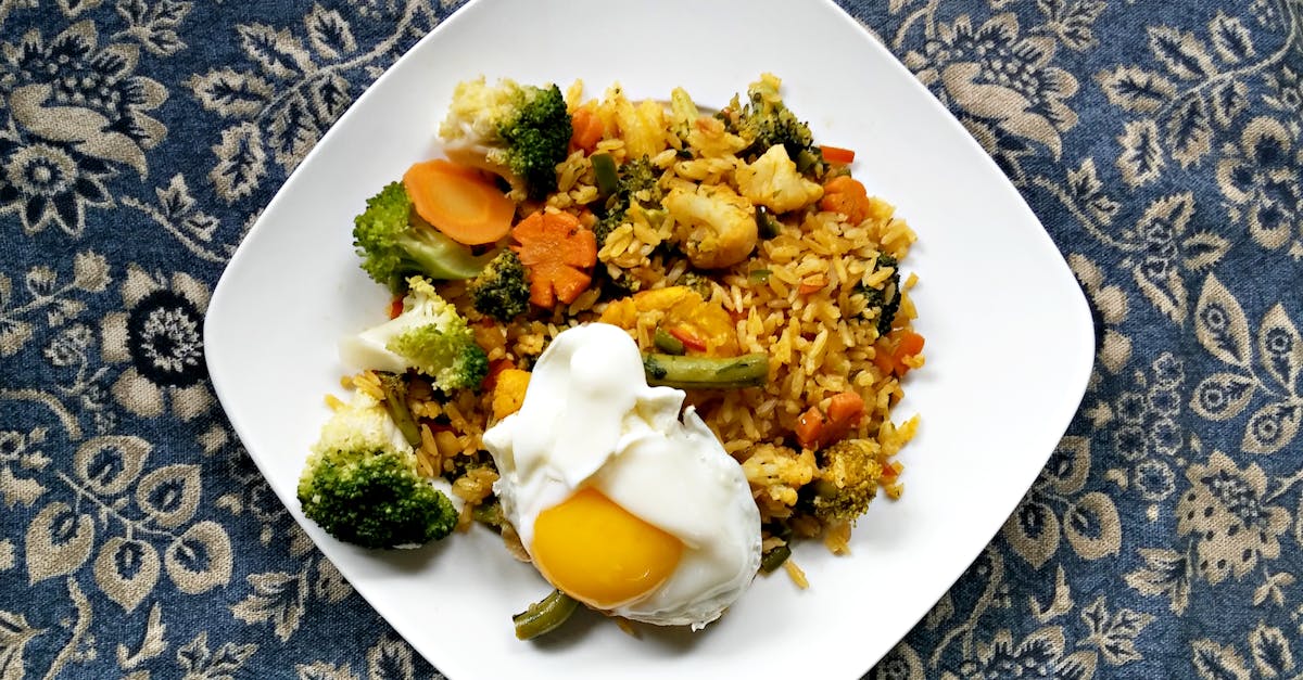 delicious vegetable fried rice topped with a sunny side up egg served on a white plate