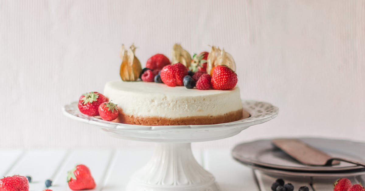 elegant cheesecake topped with fresh strawberries and berries on a cake stand