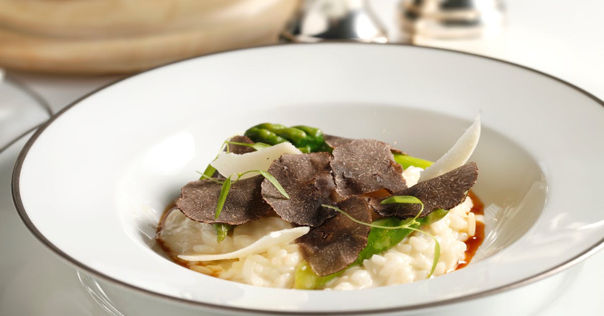 elegant truffle risotto garnished with asparagus and parmesan on a white plate