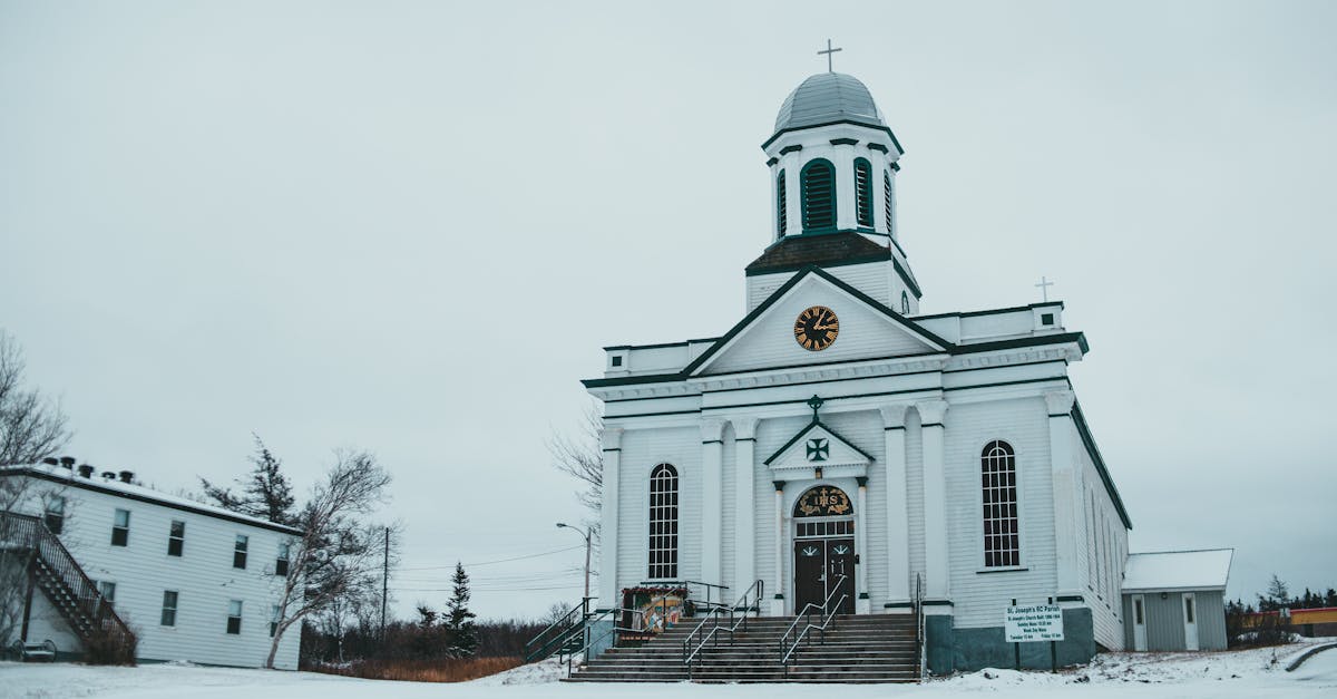 facade of st josephs church with clock and crosses located on snowy street near building in st georg