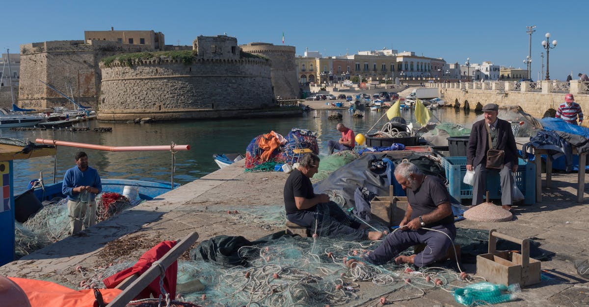 fishermen mending nets by the medieval castle in gallipoli italy