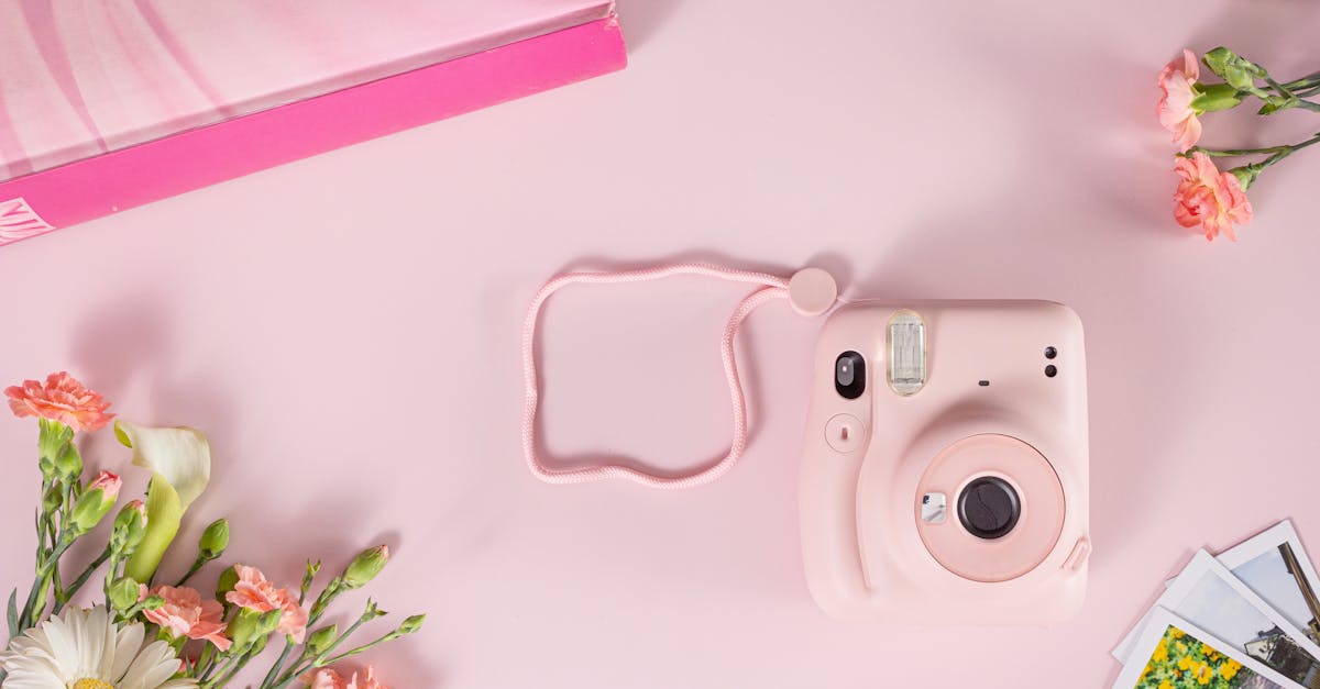 flatlay of a pink instant camera with flowers on a pastel pink background