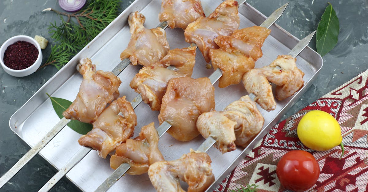 fresh raw chicken pieces on metal skewers ready for grilling surrounded by herbs and spices 1