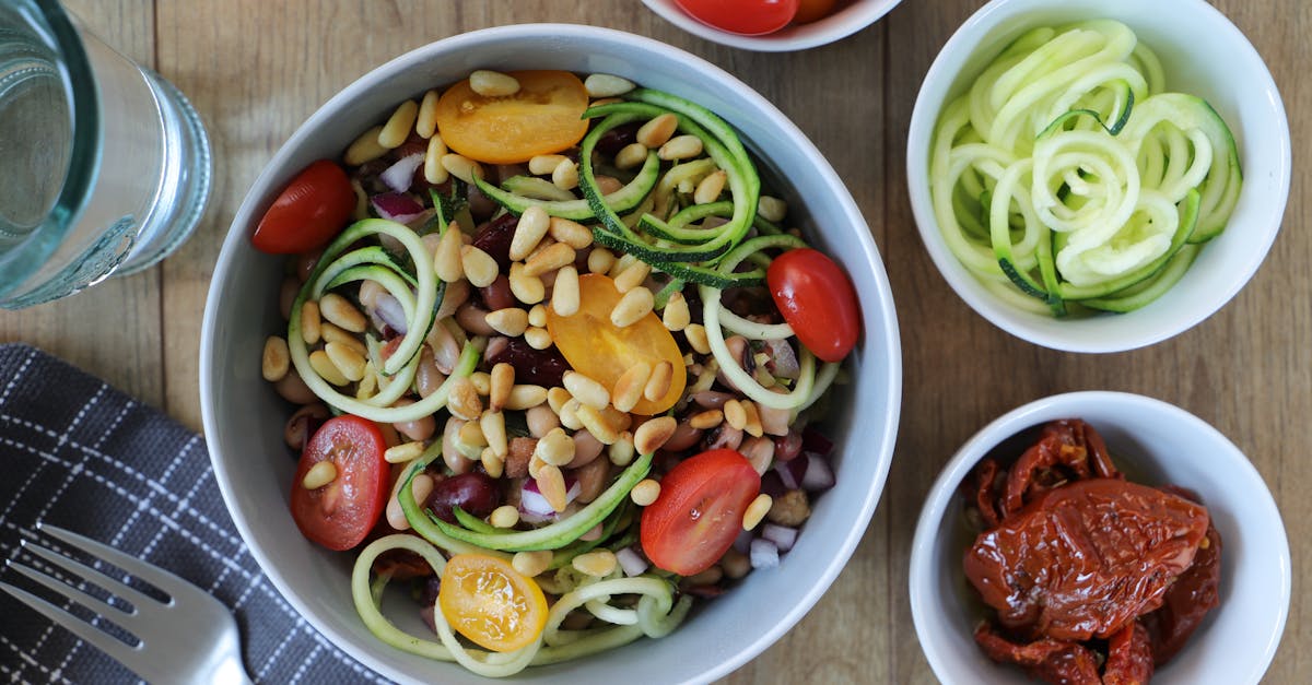 fresh zucchini noodle salad topped with tomatoes and pine nuts for a healthy meal