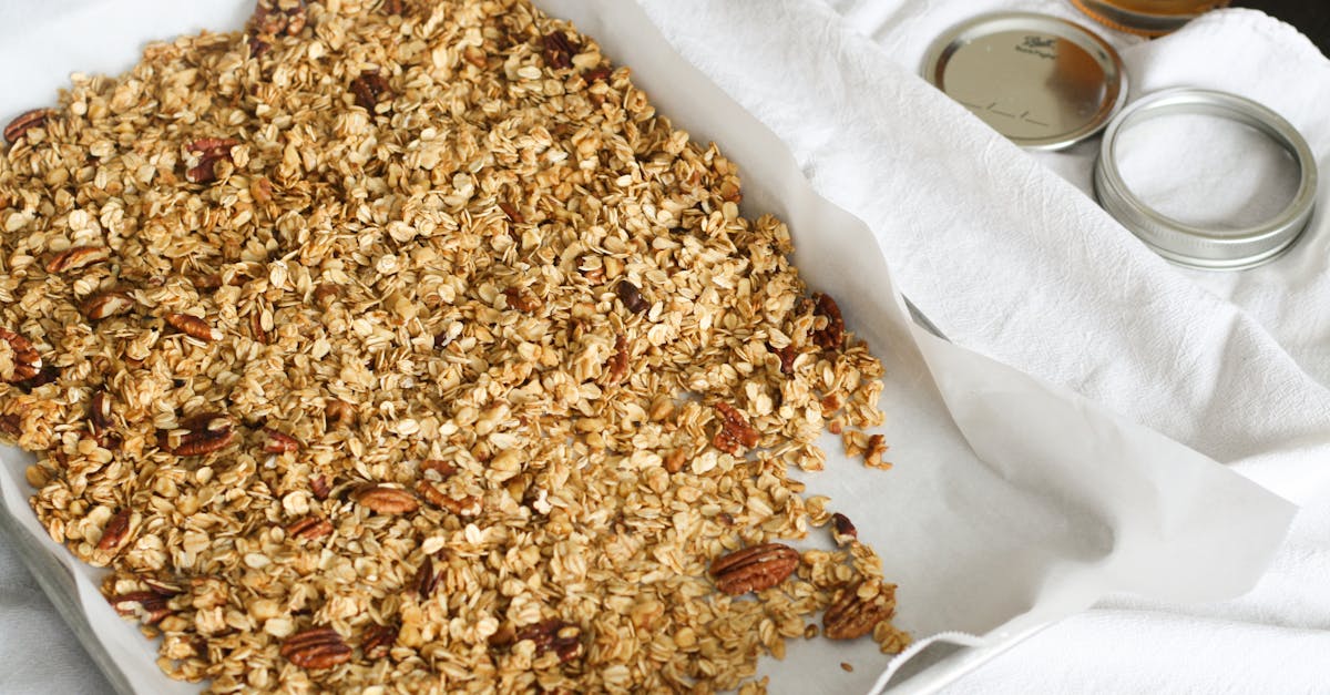 freshly baked homemade granola with oats and nuts on a tray next to a honey jar 1