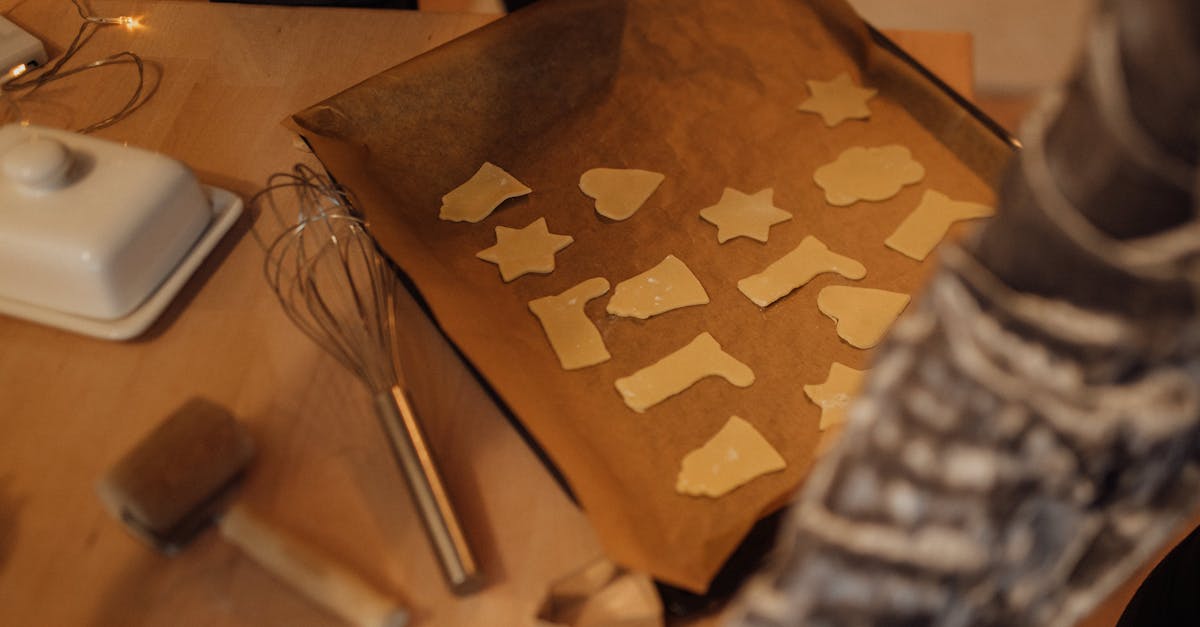 freshly cut cookie dough in various shapes on baking tray with whisk nearby