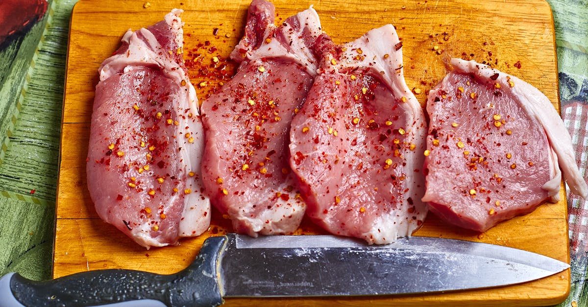 freshly seasoned pork chops with spices on a wooden chopping board ready for cooking