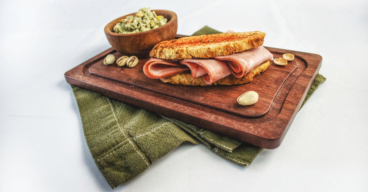 gourmet ham sandwich with pistachios and dip on wooden board perfect for food photography 2