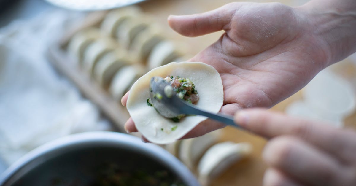 hand crafting dumplings with filling using spoon dough on table food preparation in progress
