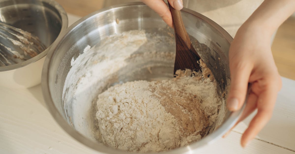 hands mixing dough with a wooden spatula in a stainless steel bowl perfect for baking themes 6