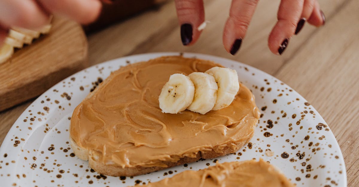 hands prepare peanut butter banana toast on artistic ceramic plate for healthy breakfast