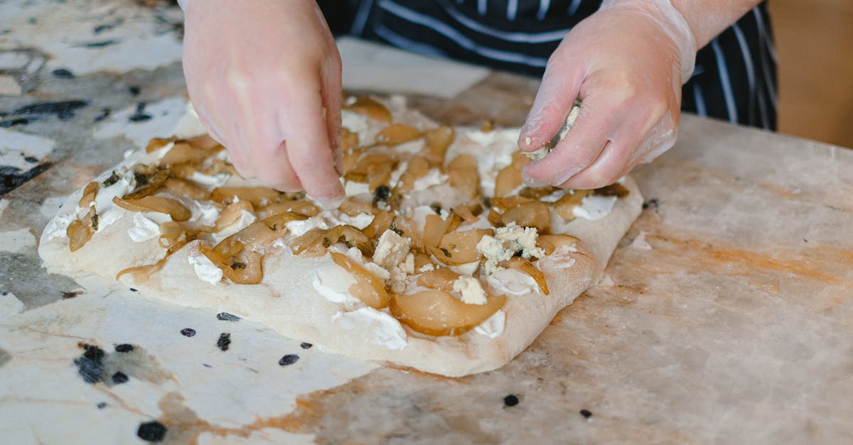 hands preparing pear and cheese focaccia on a marble counter with gloves 1