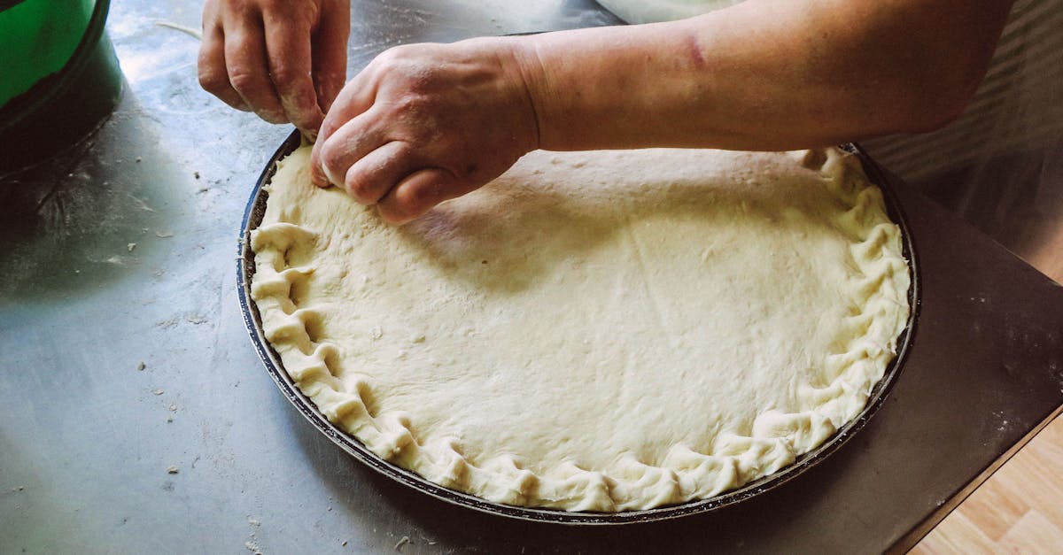 hands shaping pie dough on a baking tray showcasing homemade food preparation