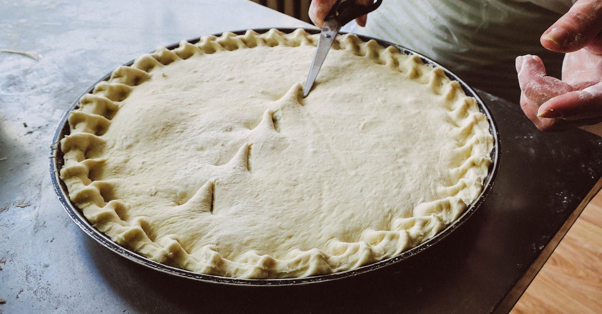 hands skillfully trimming homemade pie crust with scissors in a kitchen setting