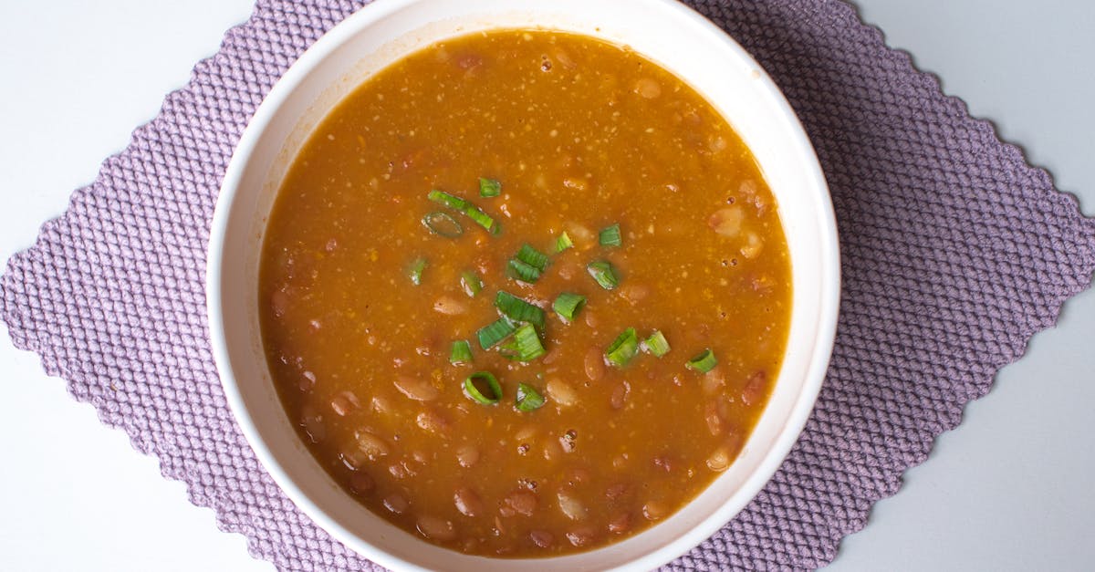 hearty homemade bean soup garnished with green onions served in a white bowl