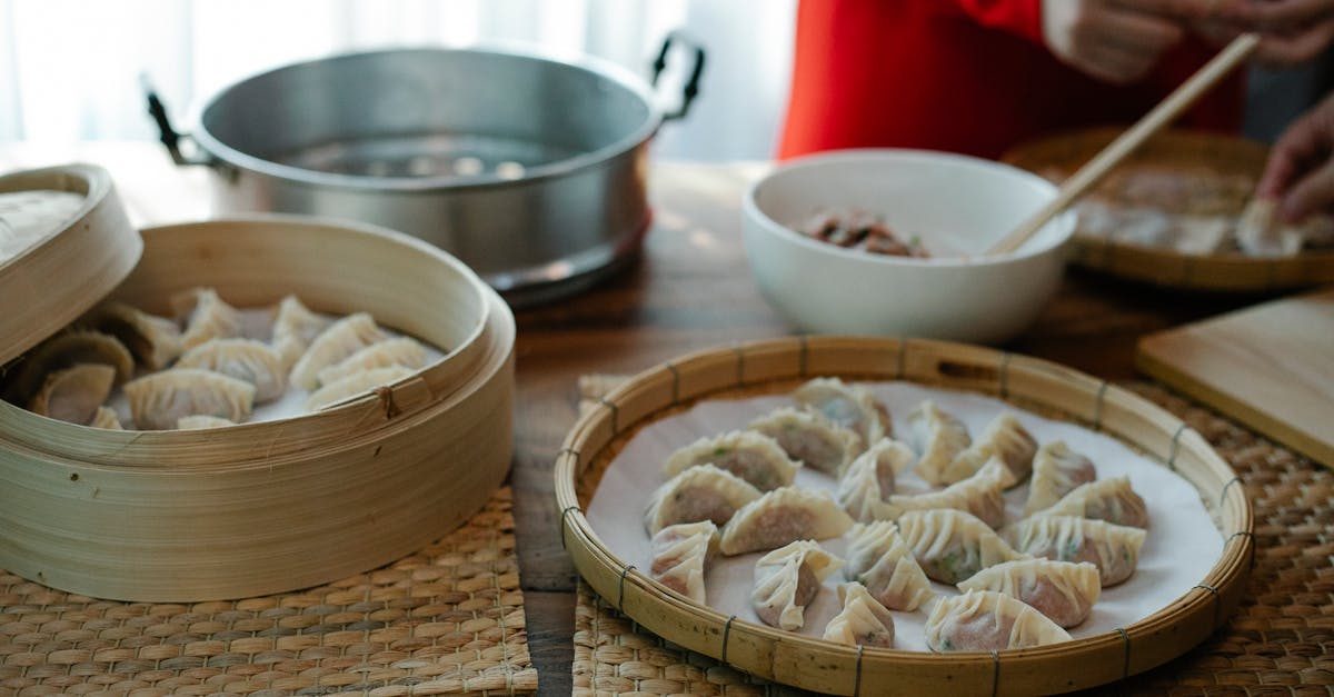 high angle of crop anonymous female folding dumplings while preparing traditional chinese jiaozi in