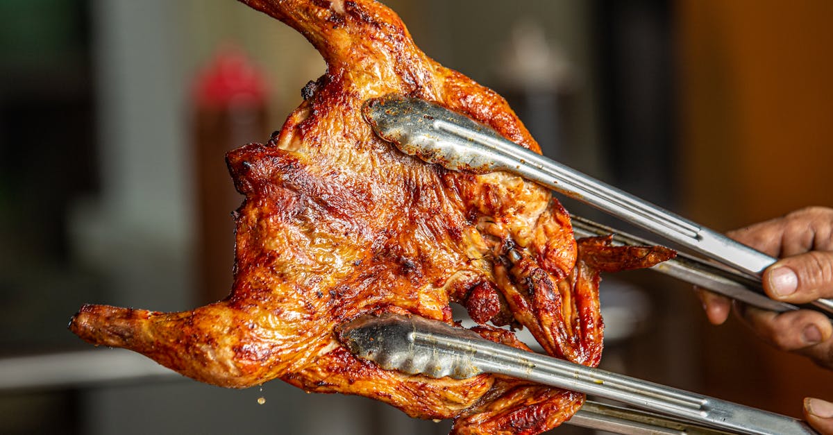 juicy roasted whole chicken fresh off the grill held with tongs perfect for bbq lovers