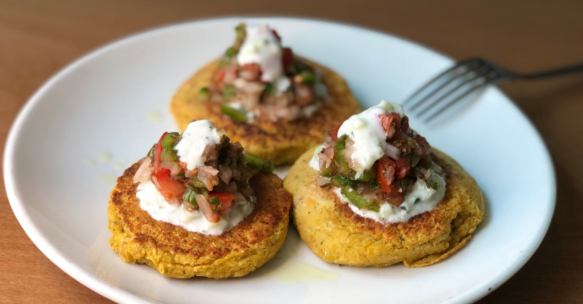 mouth watering zucchini fritters topped with fresh salsa and yogurt on a ceramic plate