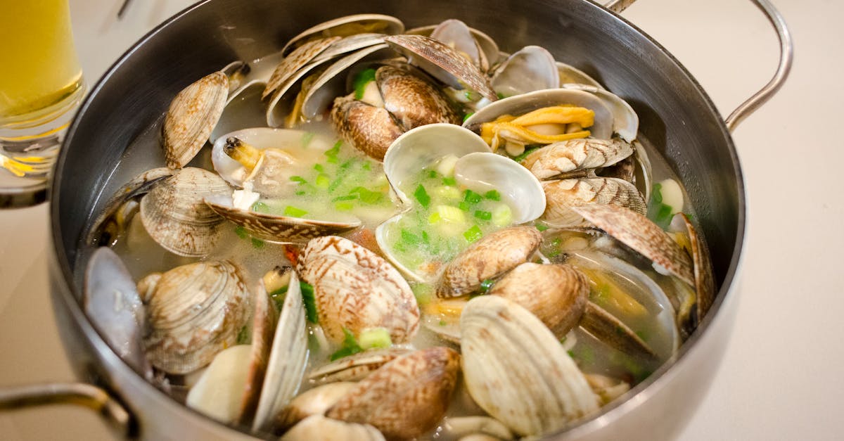 overhead view of a fresh clam soup simmering in a pot with herbs and broth ready for serving