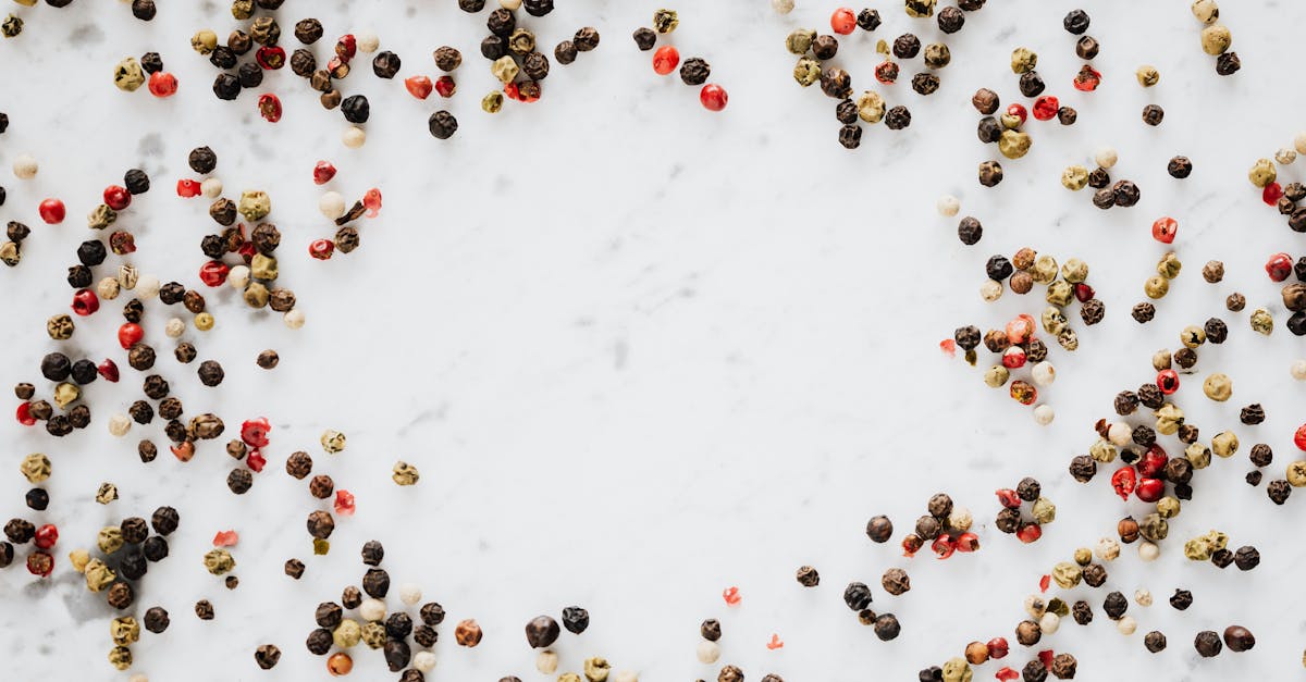 overhead view of assorted peppercorns scattered on a white marble surface 5