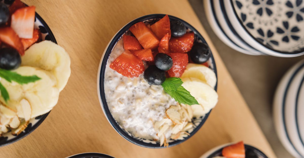 Home overhead view of oatmeal bowls topped with fresh fruits like bananas strawberries and blueberries