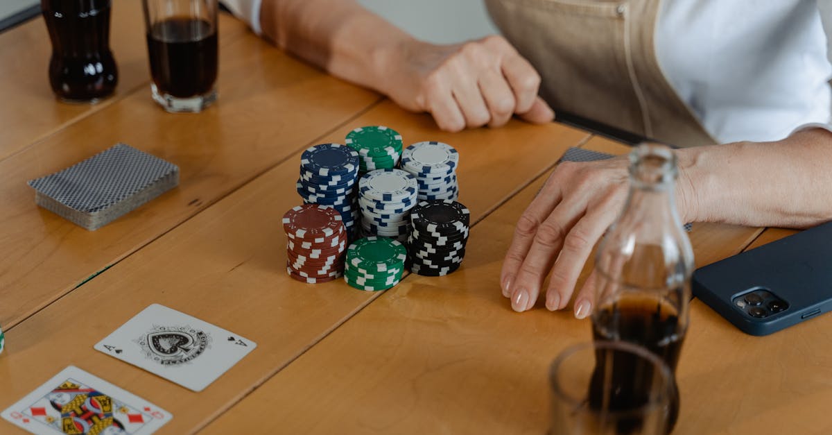 people playing poker with cards and chips on a wooden table enjoying drinks