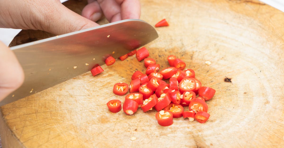 Home person slicing fresh red chili peppers on a wooden chopping board