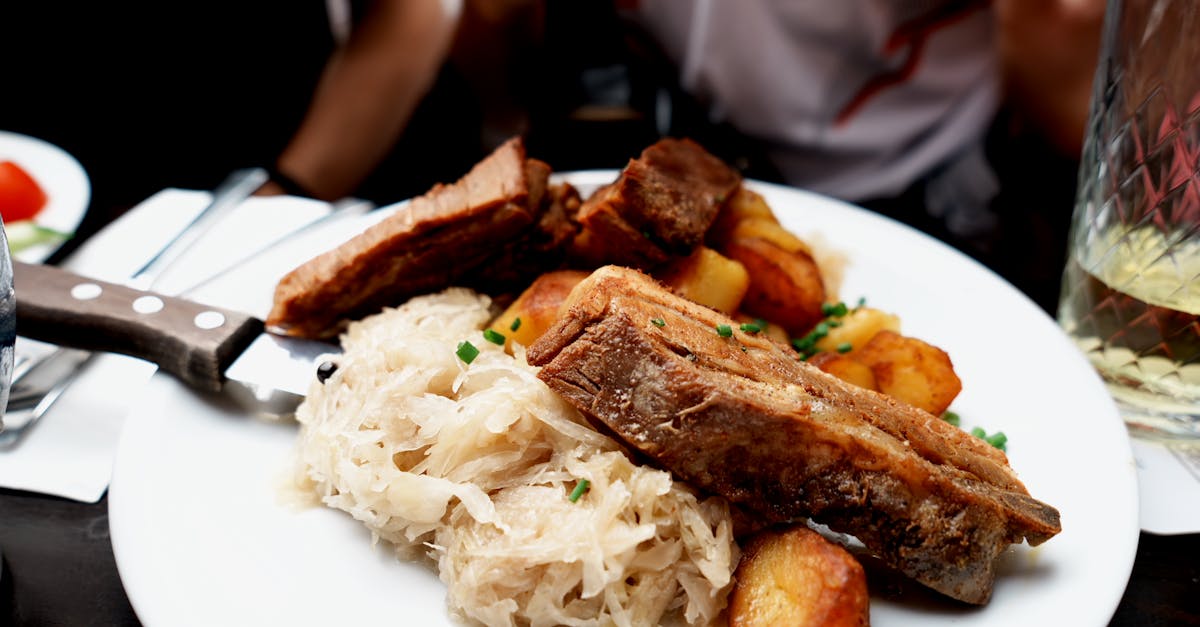 plate of roast pork ribs sauerkraut and potatoes served in a cozy setting