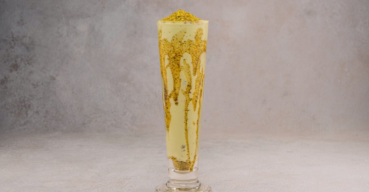 refreshing mango lassi in a tall glass with crunchy toppings on a gray background