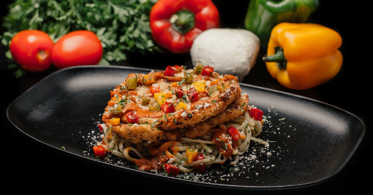 savor a mouthwatering dish of chicken pasta garnished with fresh vegetables on a stylish black plate 2