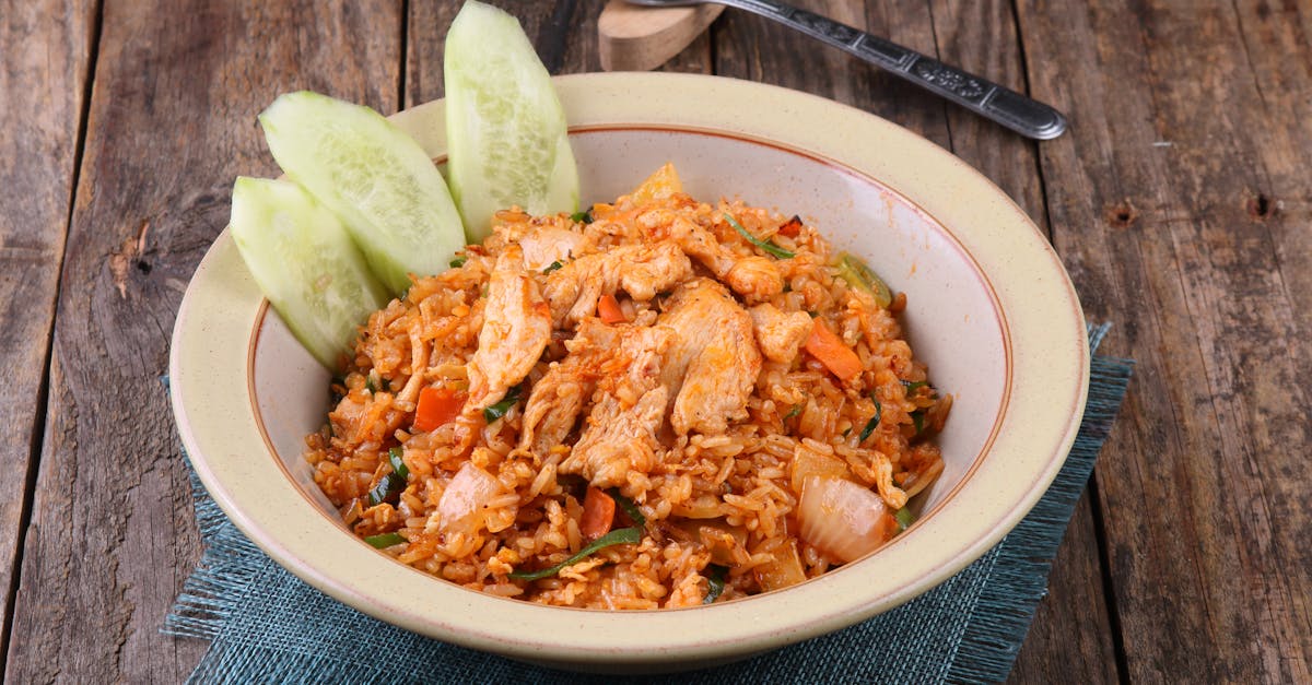 savory chicken fried rice served with fresh cucumber slices on a rustic wooden table
