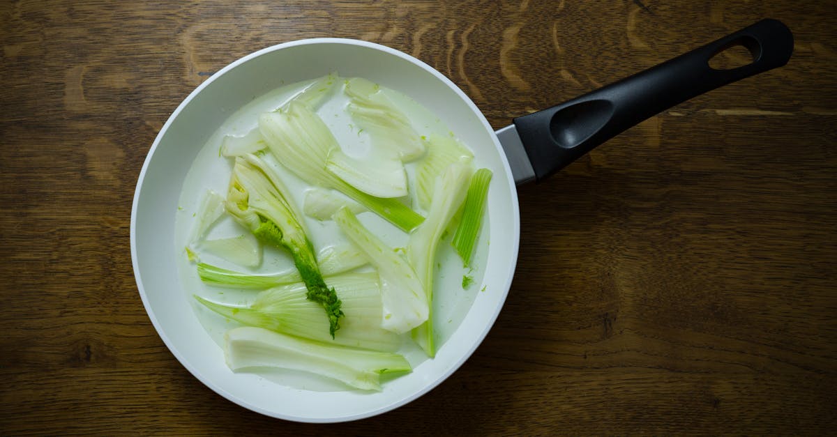 sliced fennel bulbs in a frying pan showcasing fresh ingredients on a wooden table