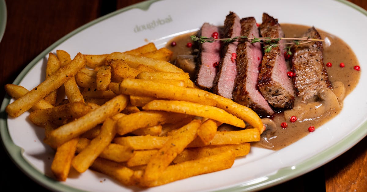 sliced steak with fries and sauce on a ceramic plate gourmet meal