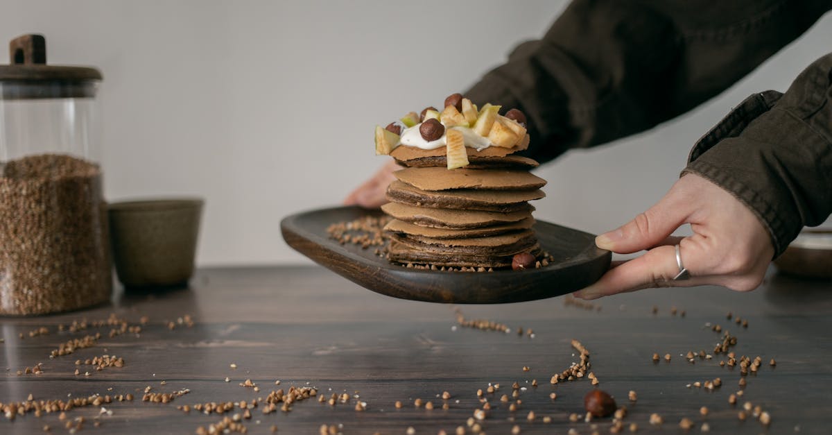 stack of buckwheat pancakes topped with fruits and nuts served on a rustic wooden plate