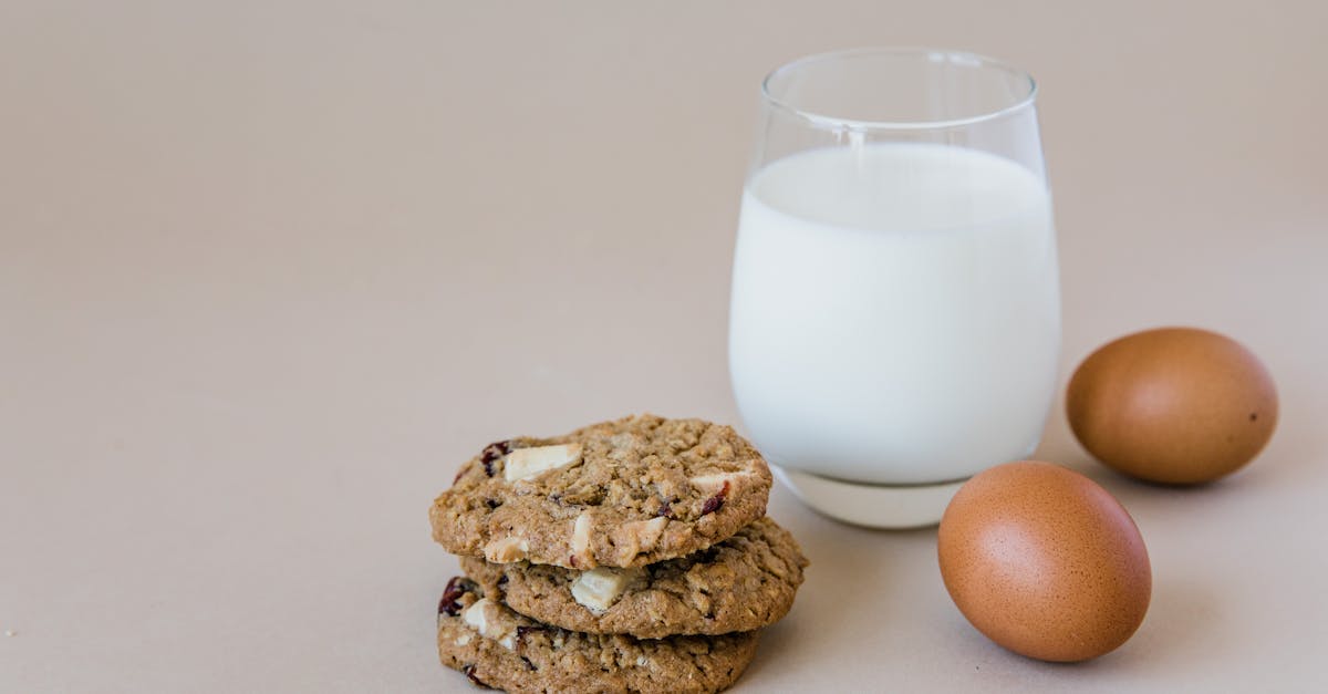stack of oatmeal cookies with milk and eggs on a neutral backdrop