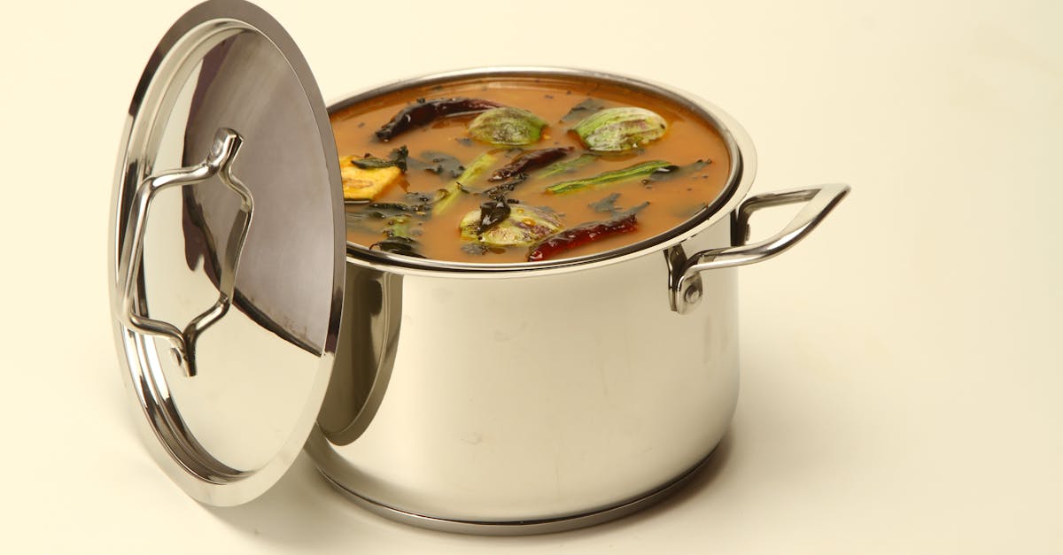 stainless steel pot filled with south indian sambar featuring vegetables and spices