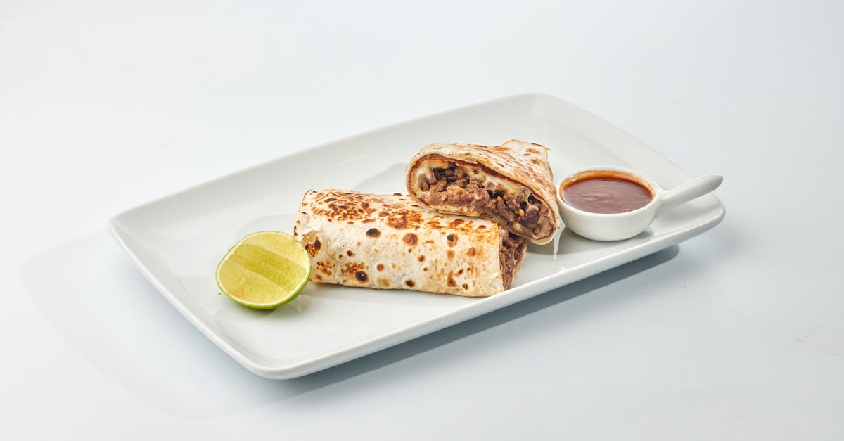 tasty beef burrito served with lime wedge and spicy salsa on a white platter