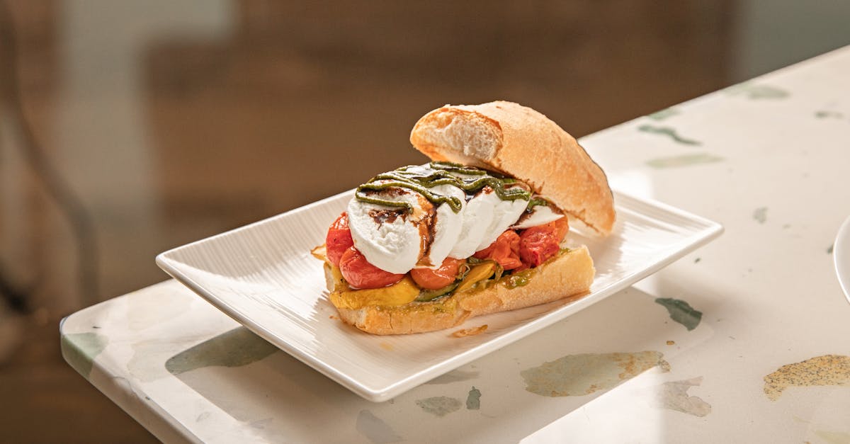 tasty sandwich with mozzarella tomatoes and pesto served on a white plate 1
