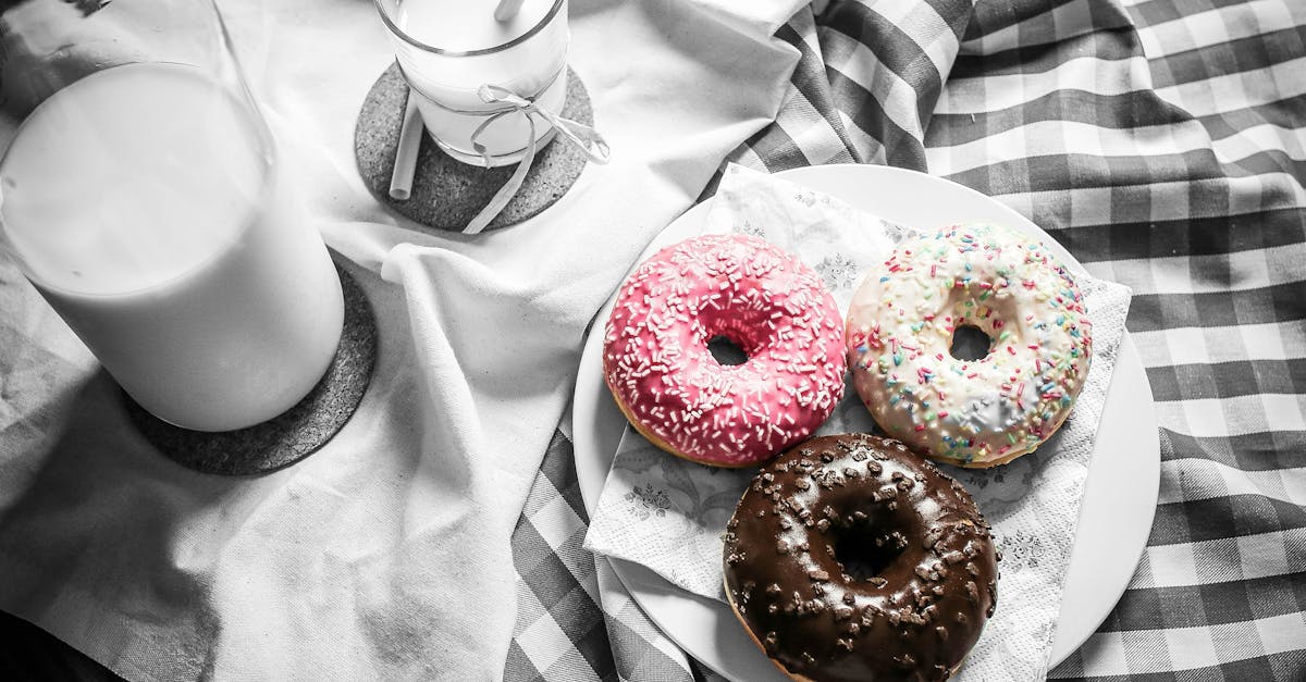 three vibrant donuts with milk on a checkered cloth creating a delightful food scene