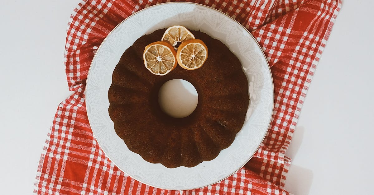 top down view of a bundt cake on red plaid fabric adorned with lemon slices