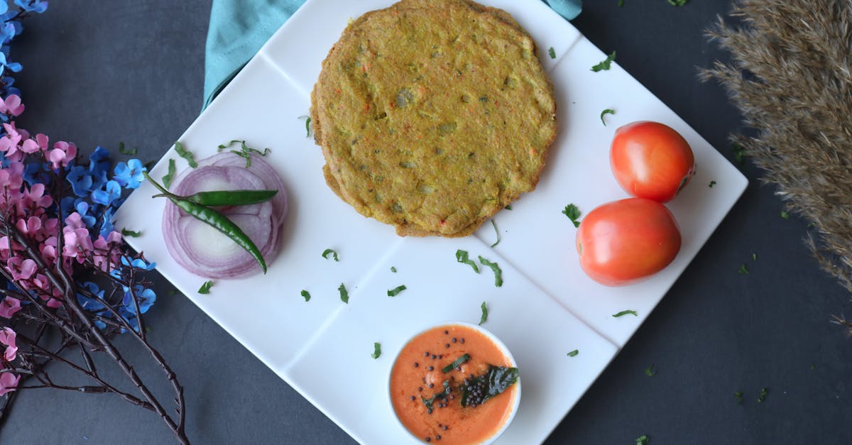 top view of a vegetable pancake on a white plate with tomato dip and garnishes