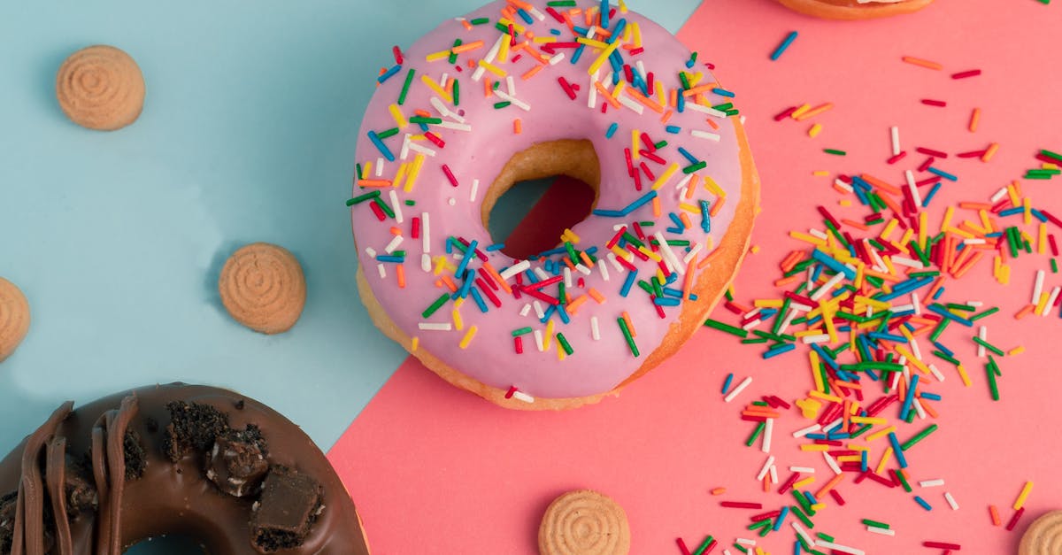 top view of colorful donuts with sprinkles and biscuits on a two tone background