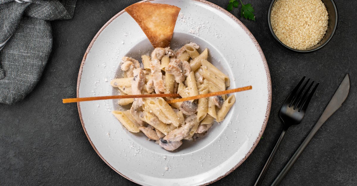 top view of creamy mushroom penne pasta garnished on a stylish plate with cutlery 1