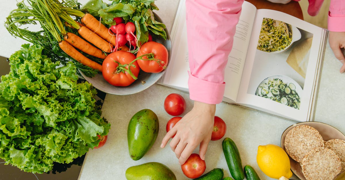 top view of fresh vegetables and hands arranging them with a recipe book promoting healthy eating 21